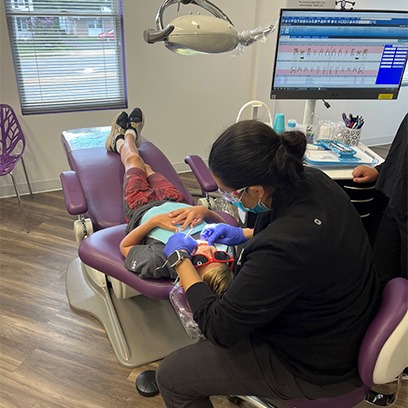 Dr. Vani Takiar cleaning a child’s teeth while they are in a dental chair