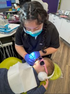 a dental hygienist applying fluoride to a child's teeth